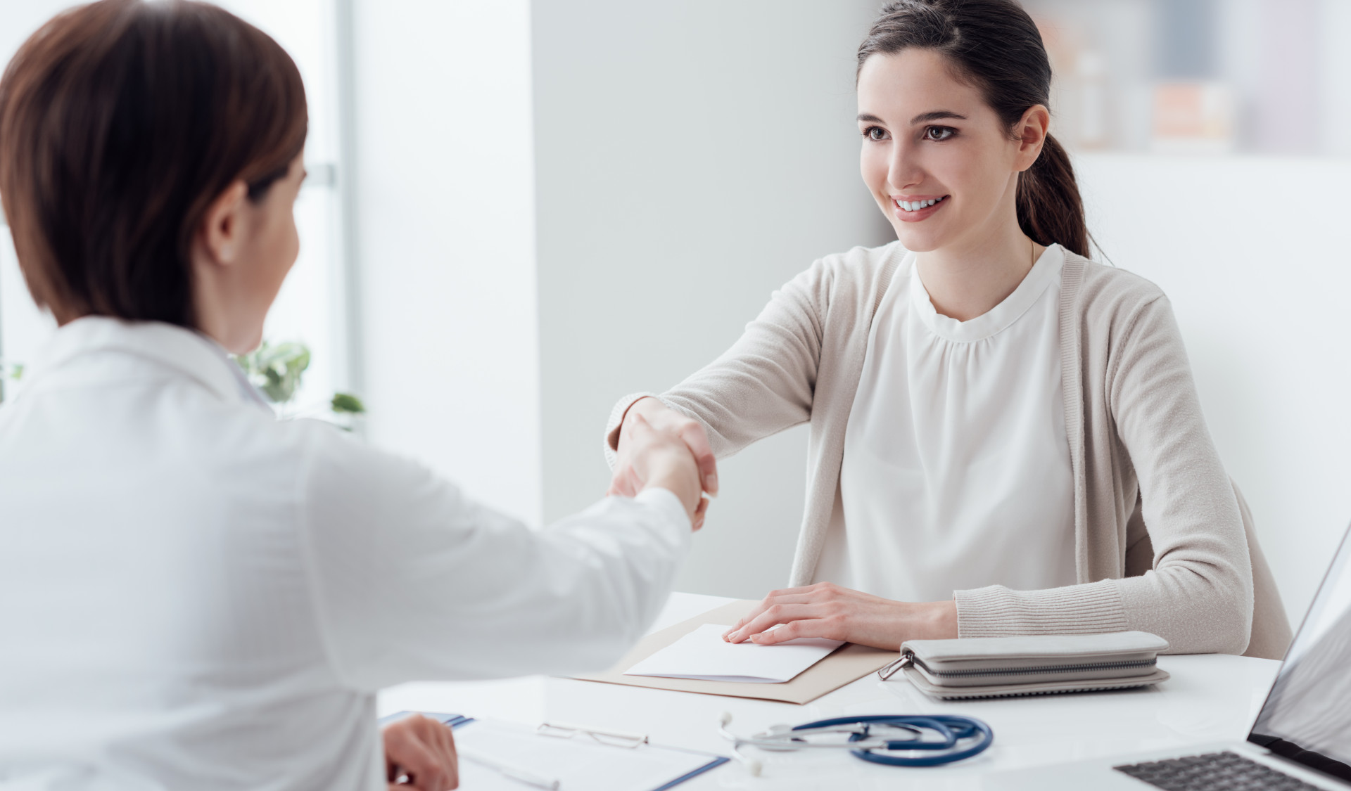 Eine Heilpraktikerin und eine Patientin reichen sich die Hand.