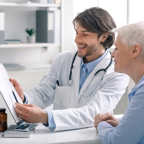 Ein Arzt zeigt einer Patientin Ergebnisse auf einem Befund.